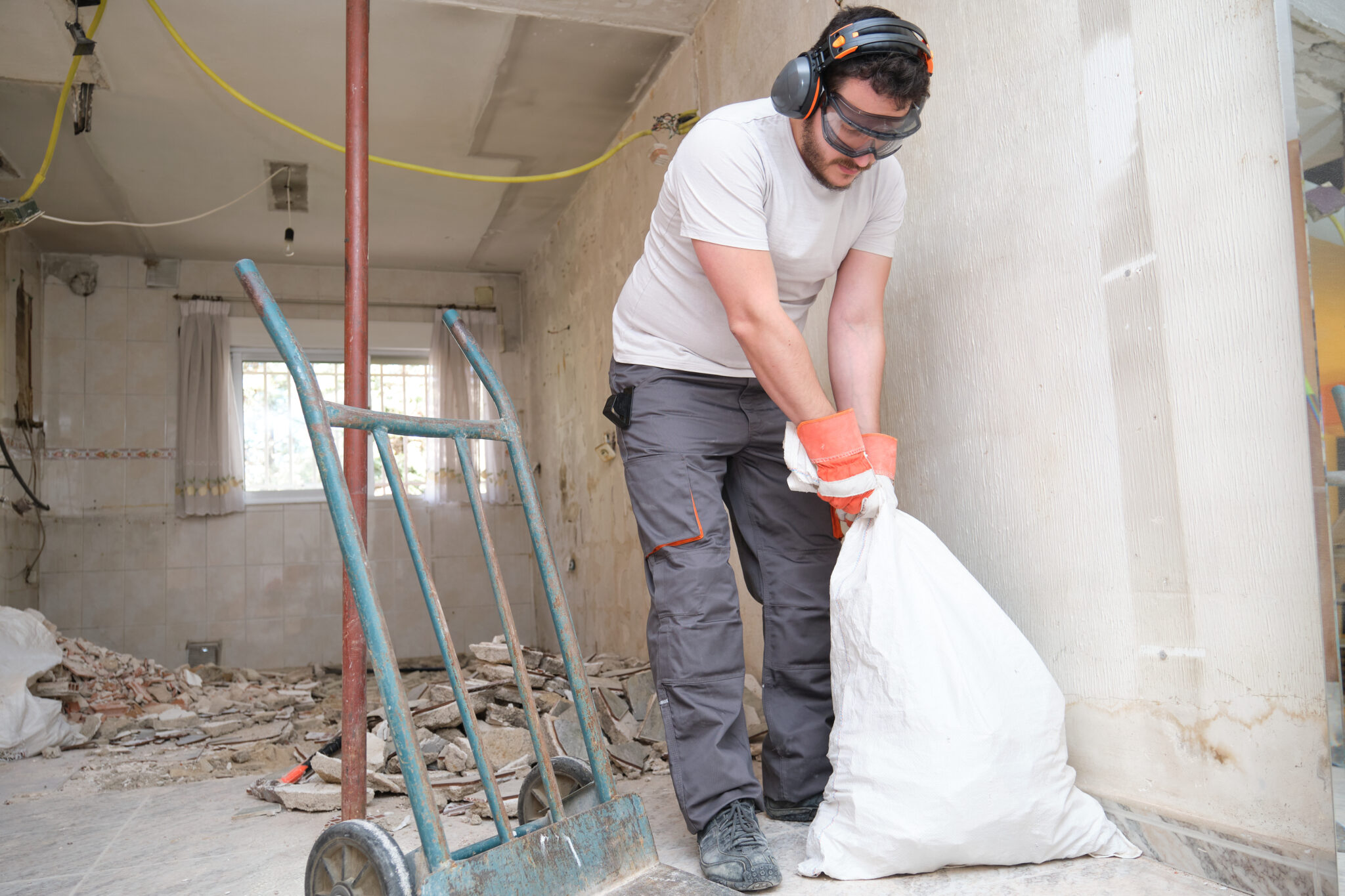 Arbeiter räumt Bauschutt und Reste auf einer Renovierungsbaustelle weg