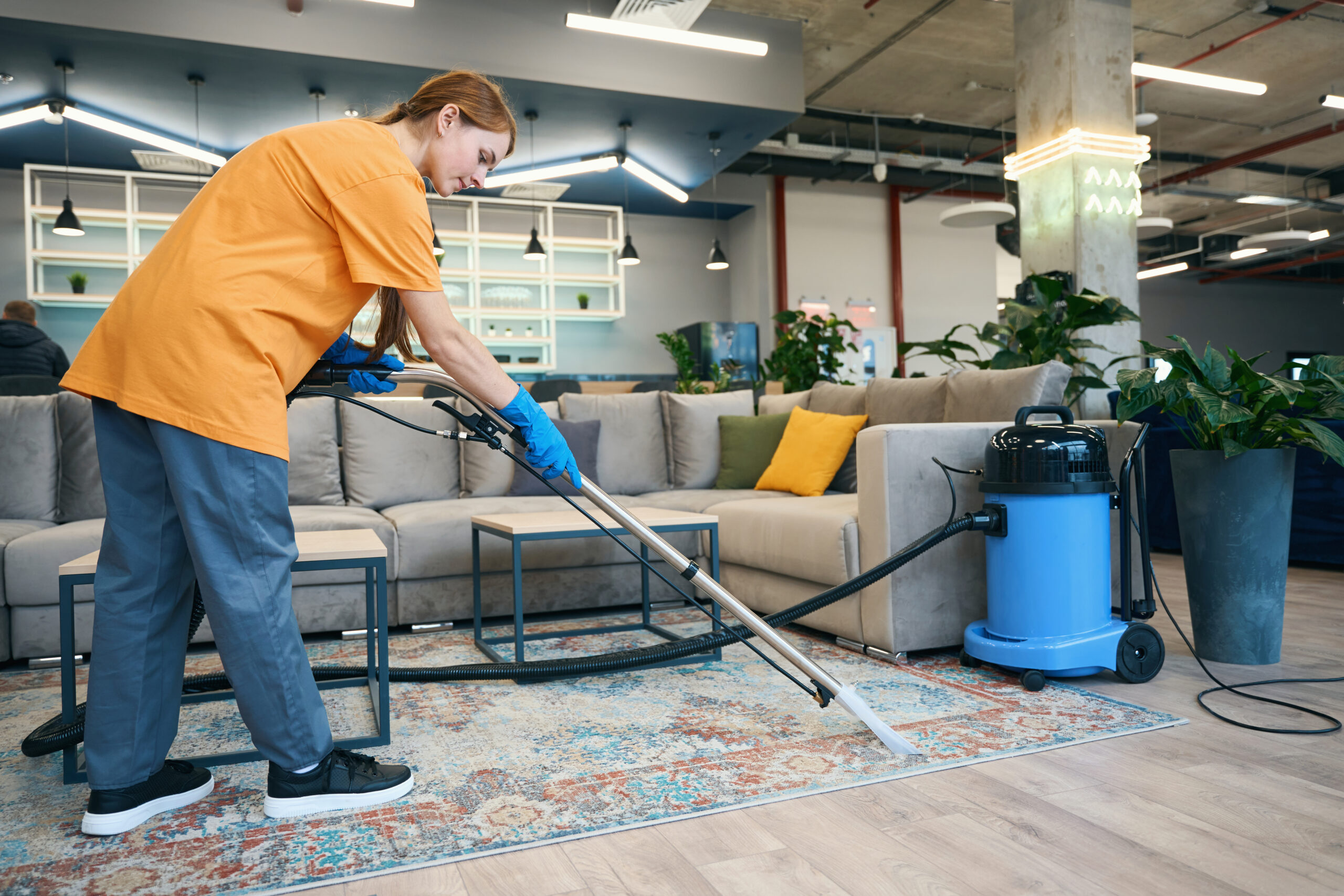 Reinigungskraft saugt Teppich in einer Bürolounge – Teppichreinigung in Mannheim mit SmartClean