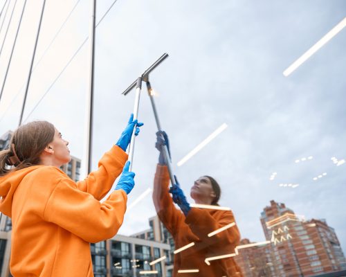 Reinigungskraft entfernt Folien- und Kleberreste vom Fenster – Baureinigung in Mannheim mit SmartClean